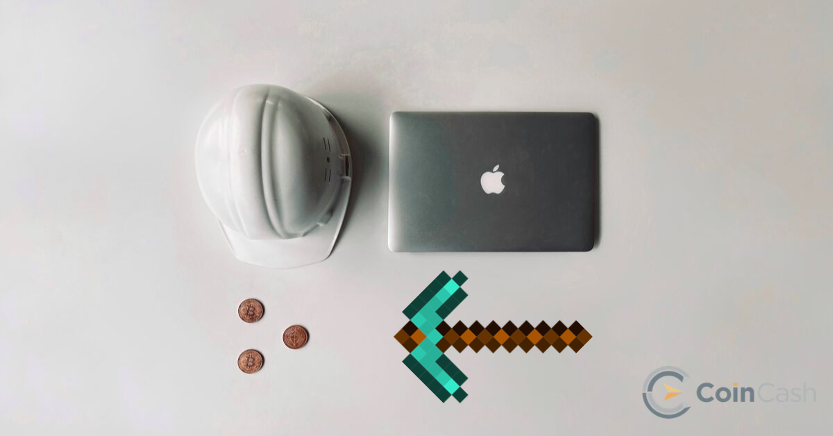 Apple MacBook, kobak, bitcoin érmék és bányász csákány egy fehér asztalon.